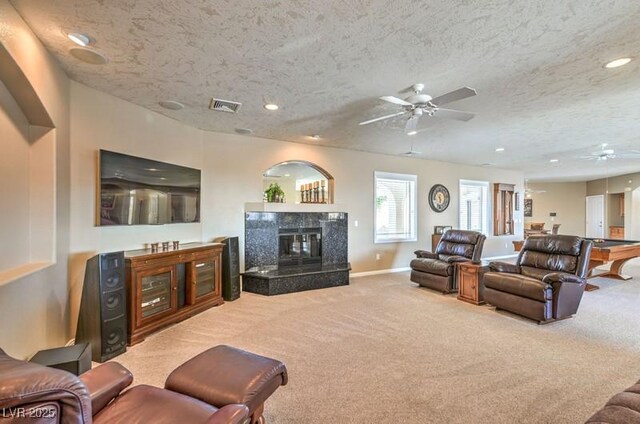 carpeted living room with a fireplace, a textured ceiling, and ceiling fan