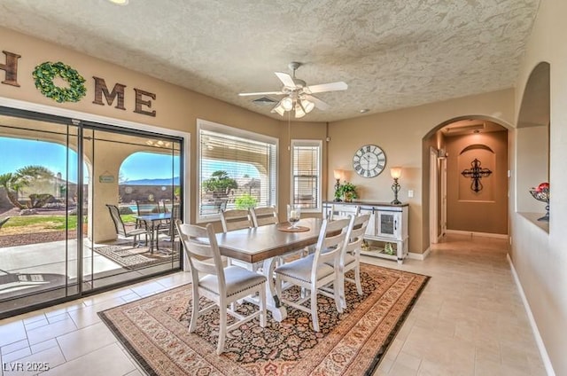 dining room with light tile patterned floors, ceiling fan, and a textured ceiling