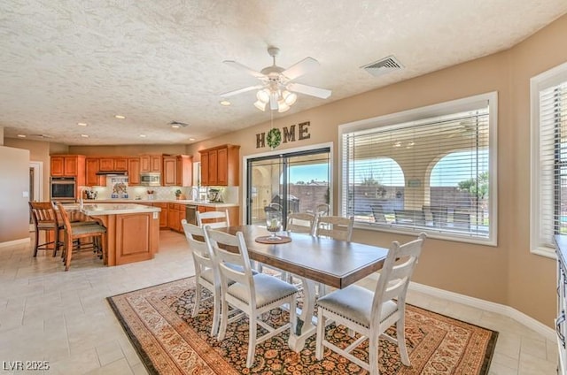 dining room featuring a textured ceiling, ceiling fan, a wealth of natural light, and light tile patterned floors