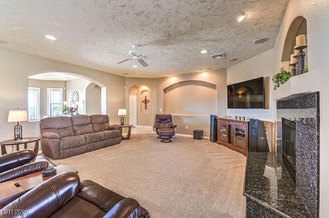 carpeted living room with ceiling fan and a textured ceiling