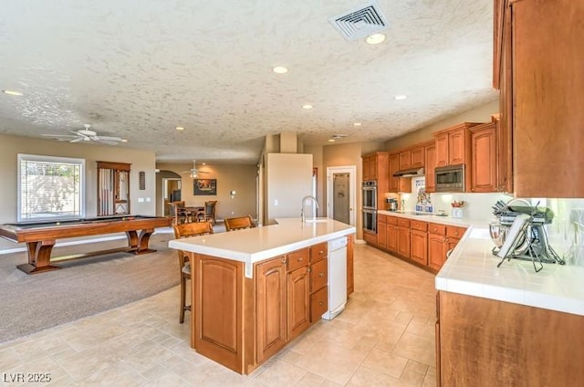 kitchen featuring a kitchen breakfast bar, stainless steel appliances, sink, pool table, and a kitchen island with sink