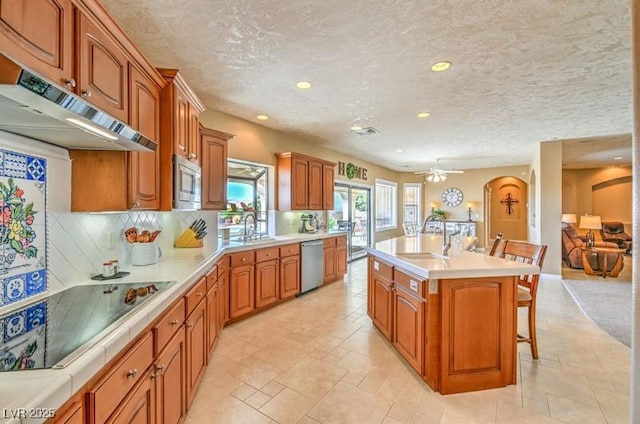 kitchen with a center island with sink, appliances with stainless steel finishes, sink, backsplash, and a breakfast bar