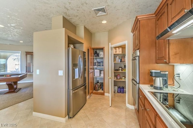 kitchen with appliances with stainless steel finishes, a textured ceiling, decorative backsplash, light tile patterned floors, and pool table