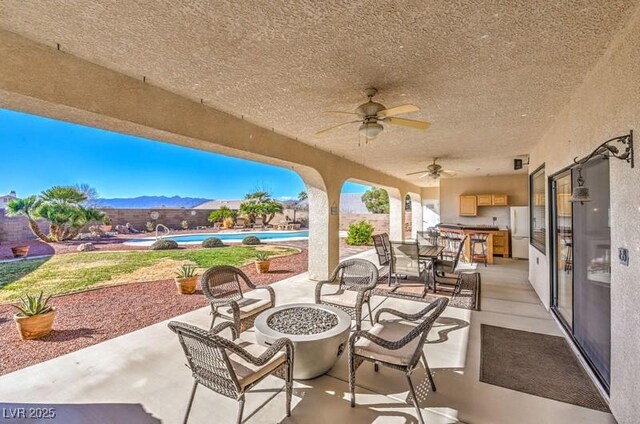 view of patio featuring an outdoor fire pit, ceiling fan, and a mountain view