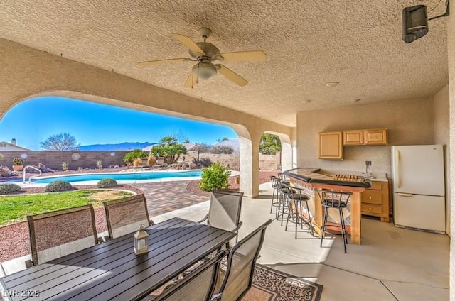 view of patio with a mountain view, ceiling fan, and exterior bar