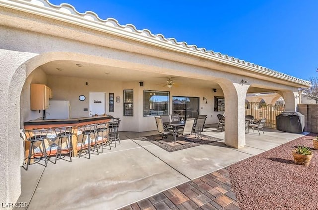 view of patio featuring a grill, ceiling fan, and a bar