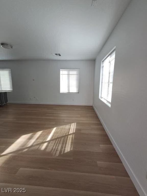 spare room with dark wood-type flooring and a wealth of natural light