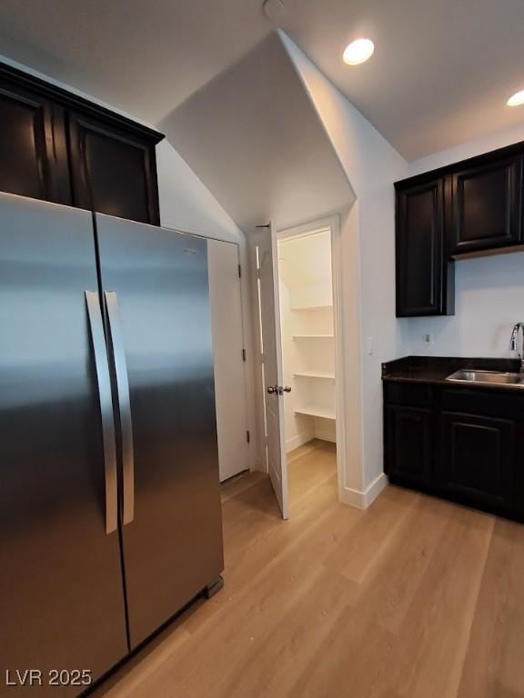 kitchen with lofted ceiling, sink, light hardwood / wood-style flooring, and stainless steel refrigerator