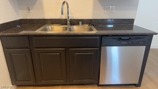 kitchen with sink, dark stone countertops, dark brown cabinetry, stainless steel dishwasher, and light wood-type flooring