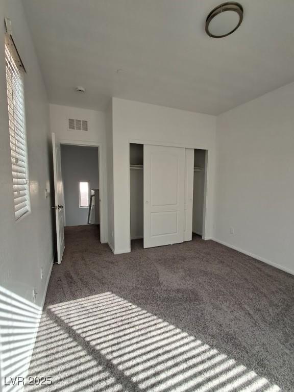 unfurnished bedroom featuring multiple windows, carpet, and a closet