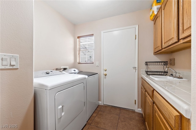 clothes washing area with separate washer and dryer, sink, cabinets, and dark tile patterned floors