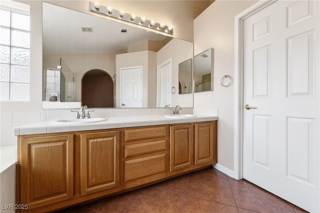 bathroom with tile patterned flooring, vanity, and walk in shower