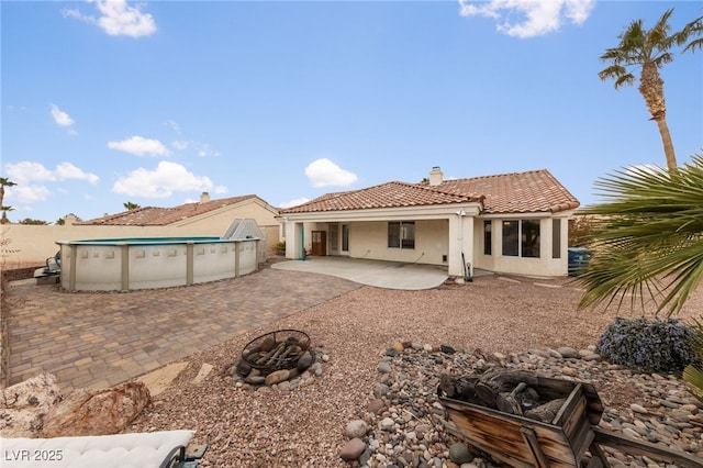 rear view of property featuring an outdoor fire pit and a patio