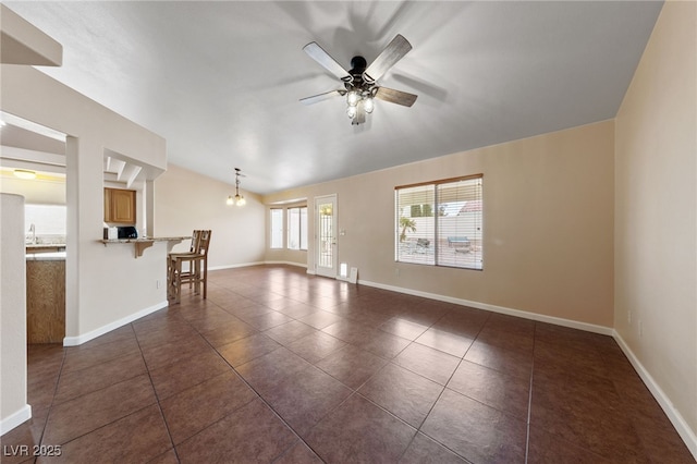 unfurnished living room featuring dark tile patterned flooring, vaulted ceiling, and ceiling fan