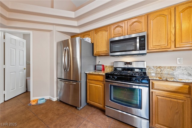 kitchen with stainless steel appliances, light tile patterned floors, and light stone counters