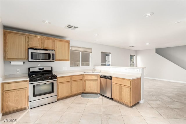 kitchen with appliances with stainless steel finishes, sink, light tile patterned floors, and light brown cabinets