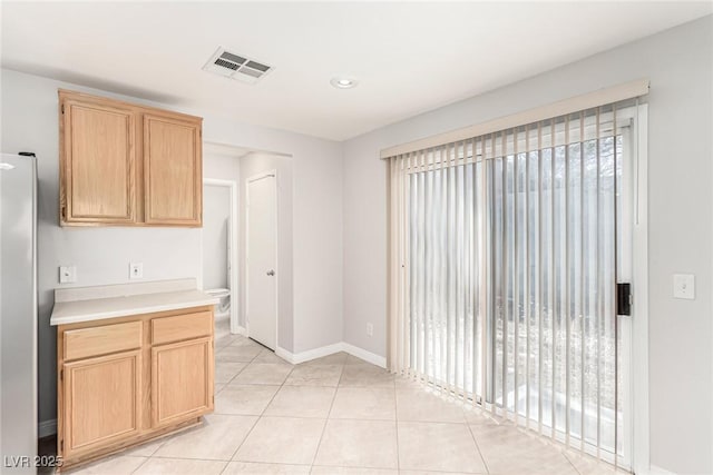 kitchen with light tile patterned flooring, light brown cabinetry, and stainless steel refrigerator