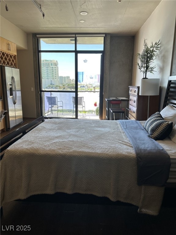 bedroom featuring multiple windows, stainless steel fridge with ice dispenser, expansive windows, and access to exterior