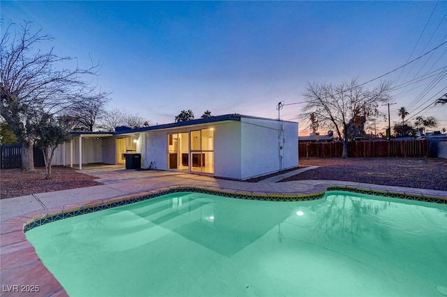 pool at dusk featuring a patio area