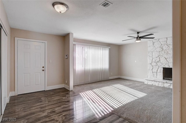 unfurnished living room featuring ceiling fan, dark hardwood / wood-style floors, and a fireplace