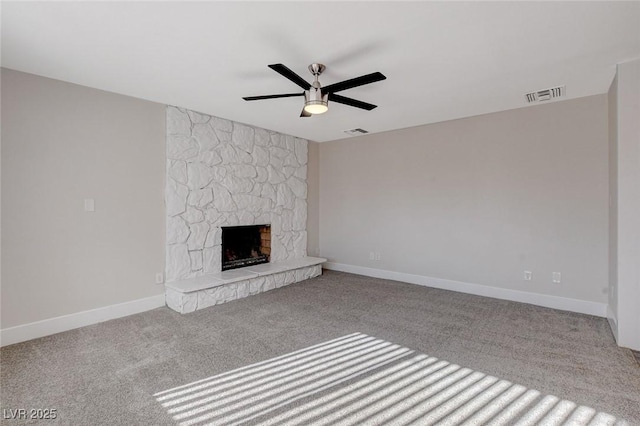 unfurnished living room with a stone fireplace, light colored carpet, and ceiling fan