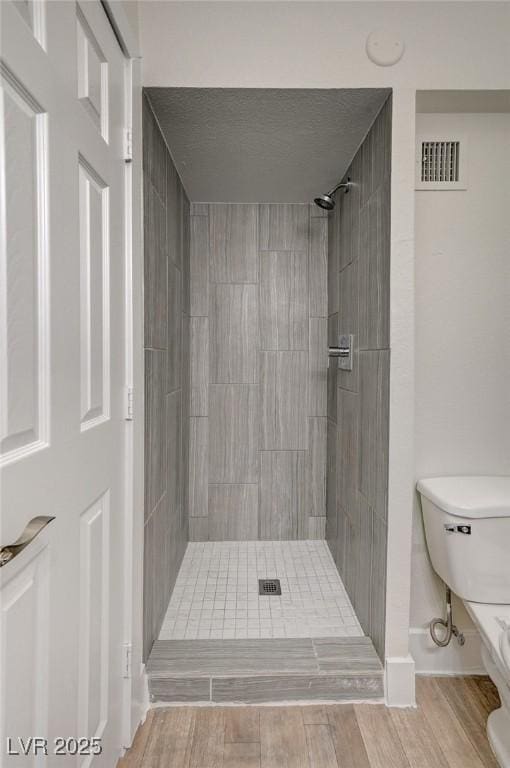 bathroom with tiled shower and toilet