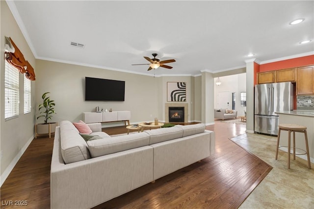 living room with crown molding, wood-type flooring, and ceiling fan