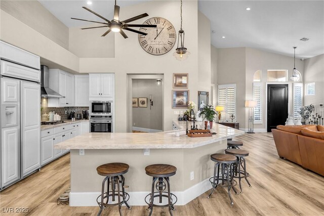 520 Summer Mesa Dr, Las Vegas, NV 89144 - kitchen with a ceiling fan, wall chimney range hood, appliances with stainless steel finishes, and high vaulted ceiling