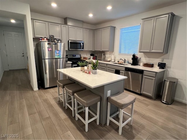 kitchen featuring a center island, stainless steel appliances, gray cabinets, and sink