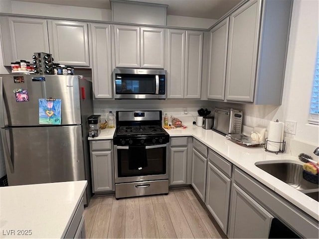 kitchen featuring light hardwood / wood-style flooring, sink, gray cabinets, and appliances with stainless steel finishes