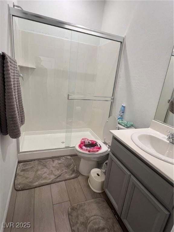 bathroom featuring vanity, a shower with door, and toilet