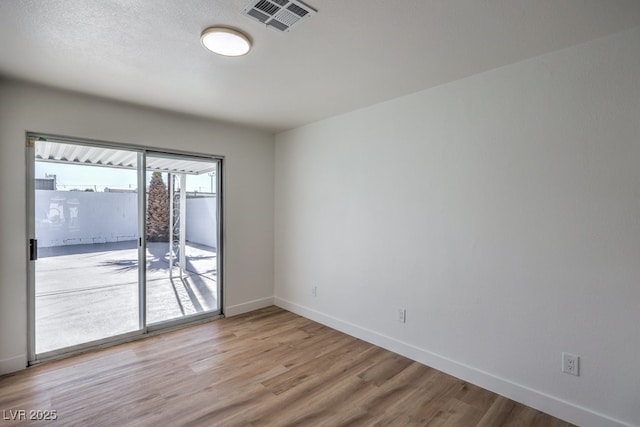 empty room with visible vents, baseboards, and wood finished floors