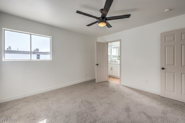 unfurnished bedroom with ensuite bath, light colored carpet, baseboards, and ceiling fan