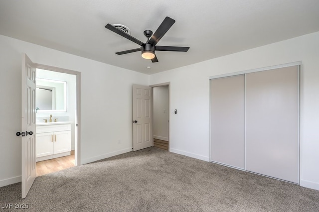 unfurnished bedroom with ensuite bathroom, sink, light colored carpet, ceiling fan, and a closet