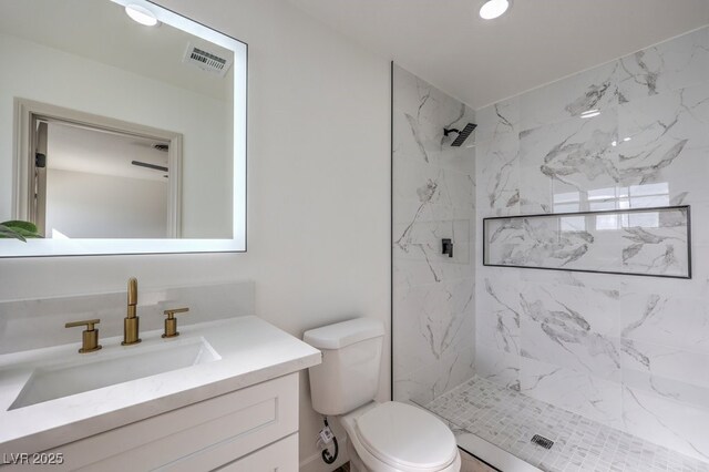 bathroom featuring vanity, tiled shower, and toilet