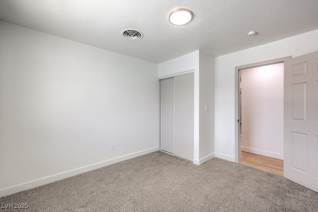 unfurnished bedroom featuring carpet, visible vents, a closet, and baseboards