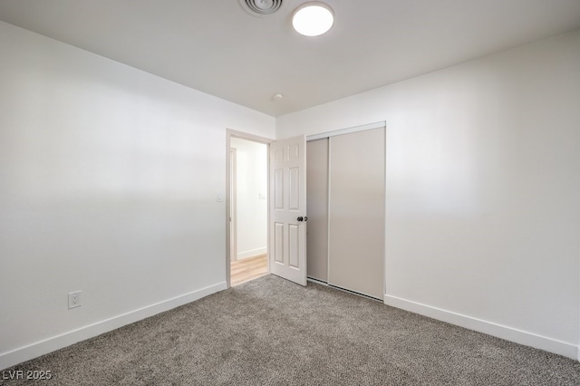 unfurnished bedroom featuring visible vents, carpet, baseboards, and a closet