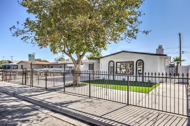 view of front of property with a fenced front yard, a chimney, and stucco siding