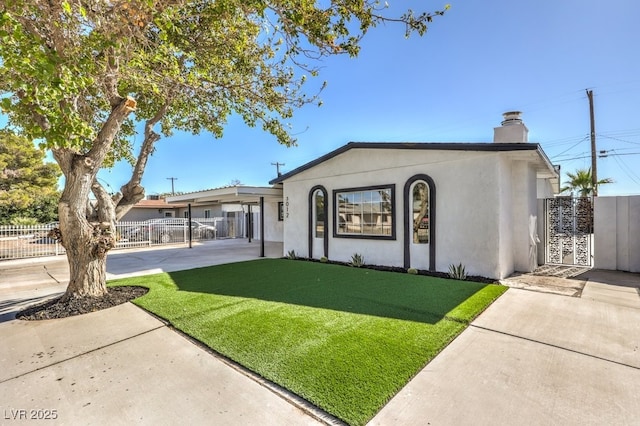 view of front facade featuring a front yard, a gate, fence, a chimney, and stucco siding