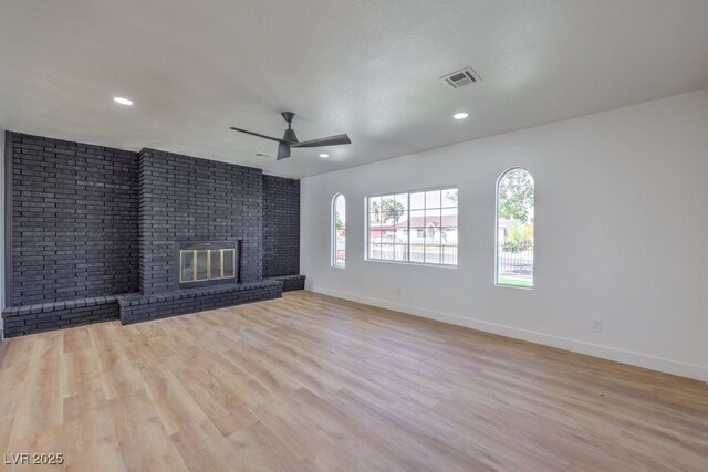 unfurnished living room featuring ceiling fan, a fireplace, and light hardwood / wood-style flooring