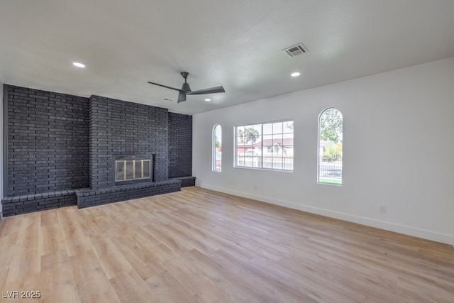 unfurnished living room with visible vents, baseboards, wood finished floors, and a fireplace