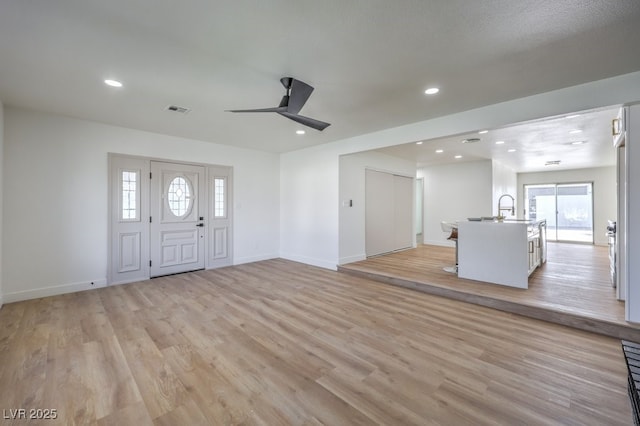 foyer entrance with ceiling fan and light hardwood / wood-style flooring