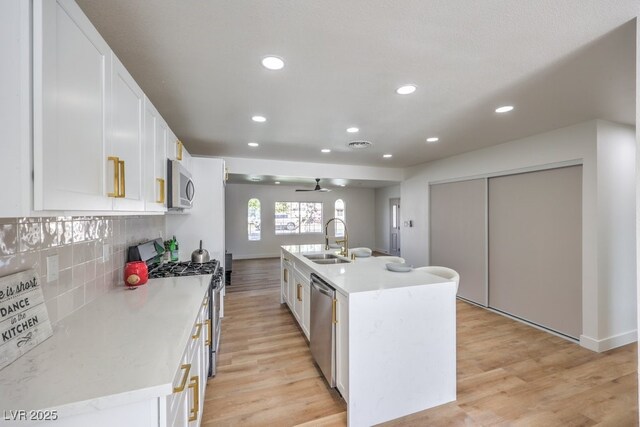 kitchen featuring sink, white cabinetry, a center island with sink, stainless steel appliances, and backsplash