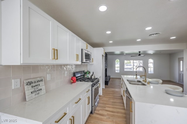 kitchen featuring tasteful backsplash, visible vents, appliances with stainless steel finishes, white cabinetry, and a sink