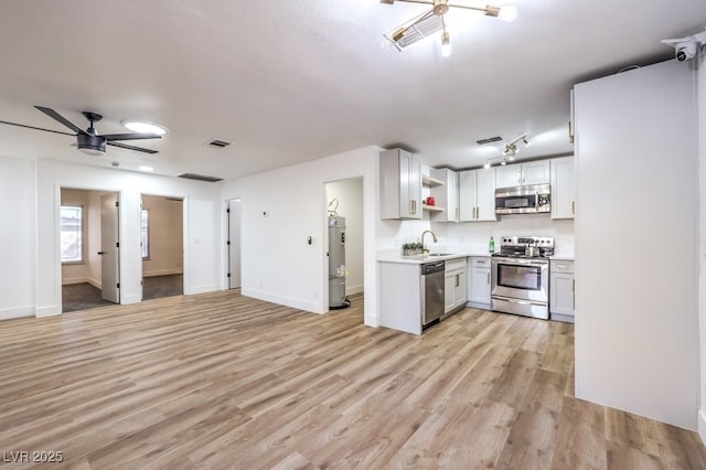 kitchen featuring sink, light hardwood / wood-style flooring, appliances with stainless steel finishes, ceiling fan, and white cabinets