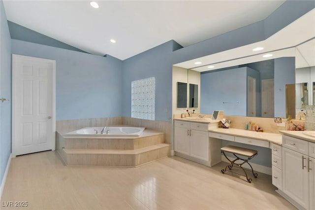 bathroom with vanity, backsplash, a relaxing tiled tub, and vaulted ceiling