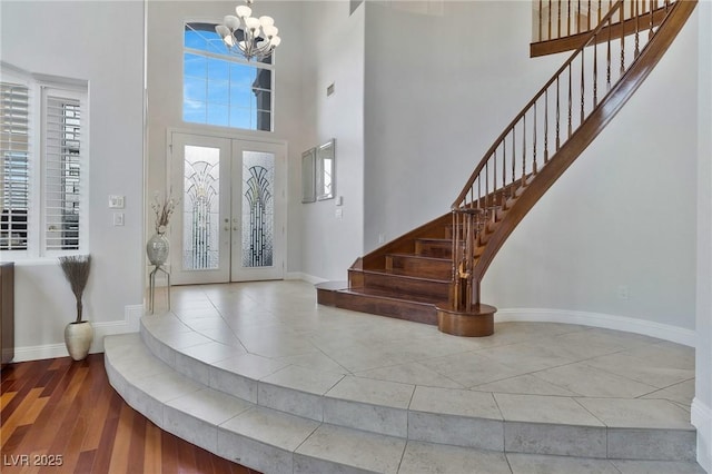 entryway with french doors, hardwood / wood-style flooring, an inviting chandelier, and a high ceiling