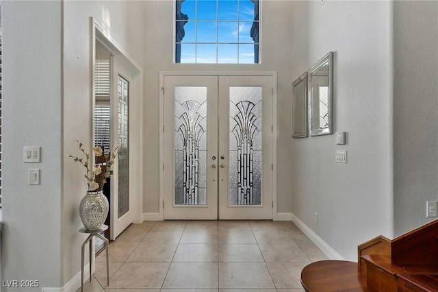 foyer with a towering ceiling, french doors, and light tile patterned flooring