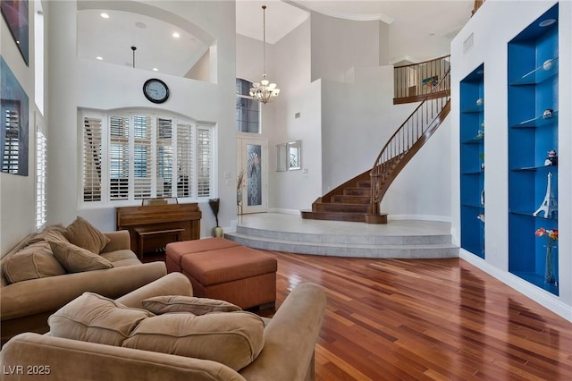 living room with an inviting chandelier, a towering ceiling, wood-type flooring, and built in features