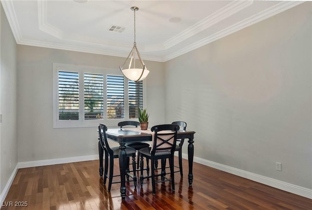 dining space featuring crown molding, a tray ceiling, and dark wood-type flooring